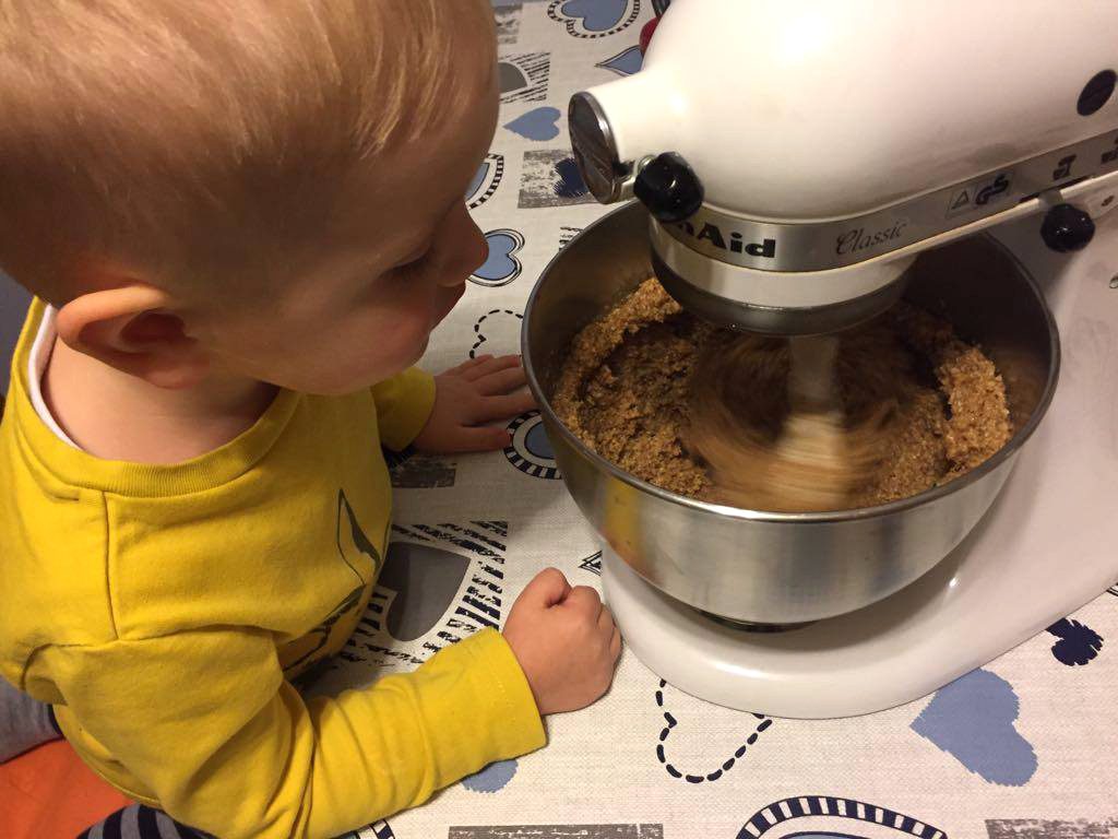 Der Junge schaut zu, wie alle Zutaten im Mixer verknetet werden.